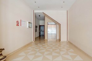 Ein Flur mit einem geometrischen Fußbodenmuster, einem Rauchverbotsschild und einem Aufzug.