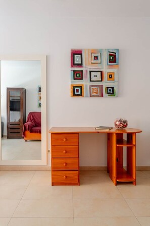 Ein Zimmer mit einem Holztisch, einem Spiegel und einem farbenfrohen abstrakten Gemälde.