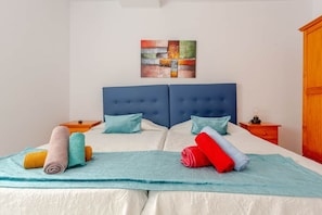 A double bed with a blue headboard, two nightstands, a wooden wardrobe, and a painting on the wall. - Welcome (Puerto del Rosario)