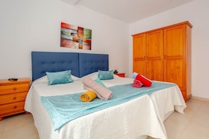 A bedroom with a large bed, a wooden wardrobe, and a painting on the wall. - Welcome (Puerto del Rosario)