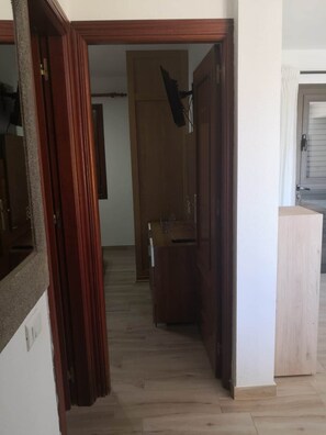 A hallway with wooden flooring, a wooden door, and a small cabinet with a mirror. - VvCasa Maruca (Internet Access - 1 GB) (Castillo Caleta de Fuste)