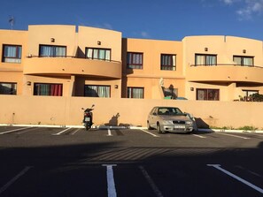 Ein mehrstöckiges Gebäude mit einem Parkplatz davor.