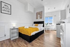 A bedroom with a bed, a bedside table, a window, and a view of the outdoors. - Gorgeous studio near Leeds City Centre - Room 5 (Leeds)