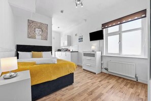 Een moderne slaapkamer met een bed, nachtkastje en een raam met zonwering.