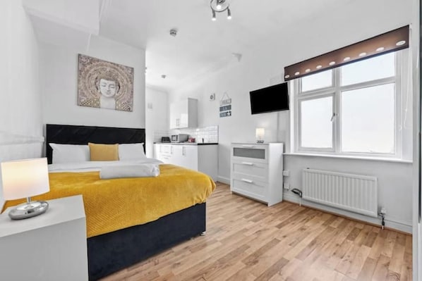 A modern bedroom with a bed, bedside table, and a window with blinds. - Gorgeous studio near Leeds City Centre - Room 5 (Leeds)