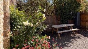 Una mesa de picnic de madera en un jardín con un muro de piedra y diversas plantas.