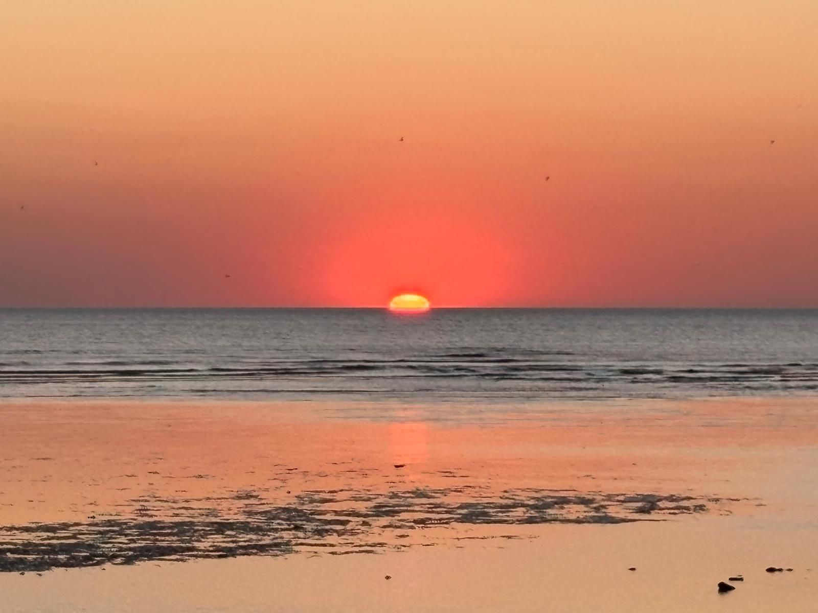 A beach with a sunset over the ocean.