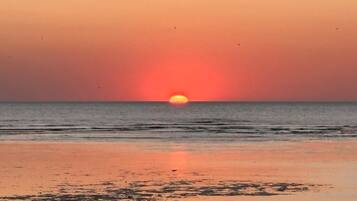 A beach with a sunset over the ocean.