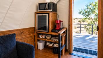 Un espacio habitable compacto con kitchenette, un estante de madera con electrodomésticos de cocina, vistas al exterior y una puerta que da a un área exterior.