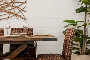 A dining table with woven placemats, two wine glasses, and a woven chair. - Heated Pool • Home Gym • Walk to Beach (Holmes Beach)