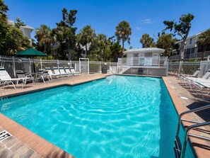 A swimming pool with a white fence and lounge chairs. - Heated Pool • Home Gym • Walk to Beach (Holmes Beach)