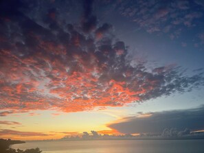 A sunset over a body of water with a silhouette of land in the distance.