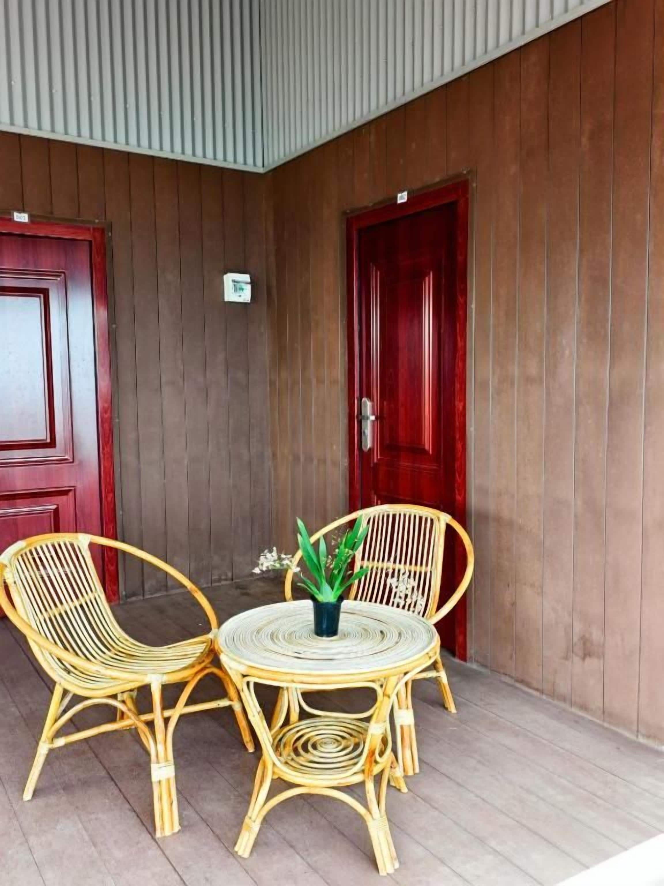 A room with two red doors, a small table with chairs, and a potted plant.