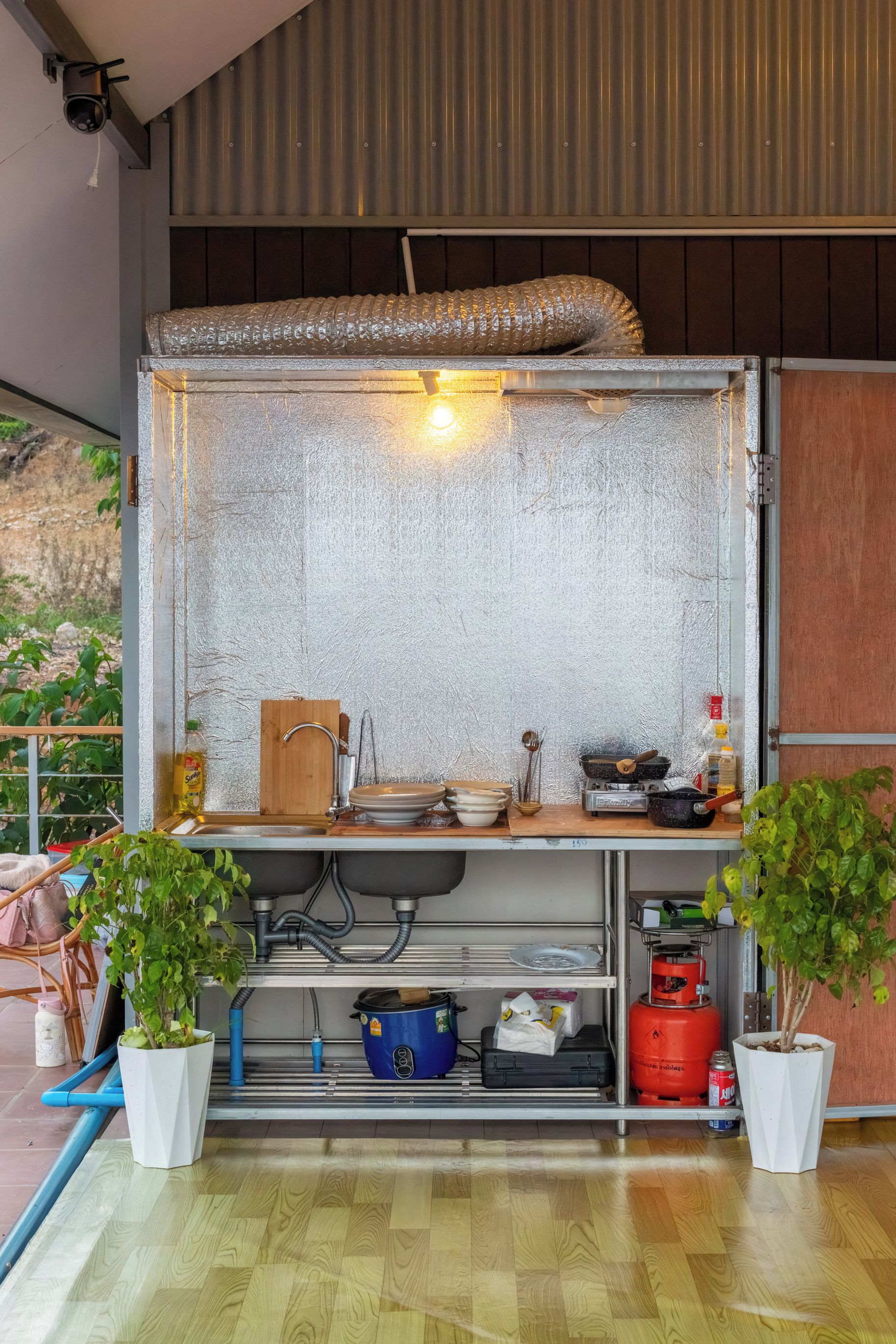 Een compacte keuken met een inbouwfornuis, spoelbak en opbergplanken.