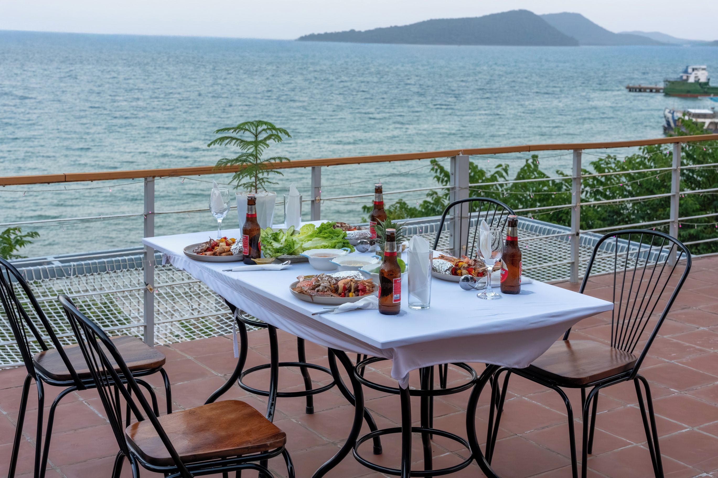 A table set for dining with a view of the sea and distant mountains.