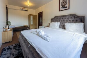A hotel room with a large bed, a bedside table, a wardrobe, and a mirror.