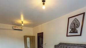 Quarto de hotel com uma cama grande, um guarda-roupa, uma mesa de cabeceira, um espelho e uma obra de arte emoldurada na parede.