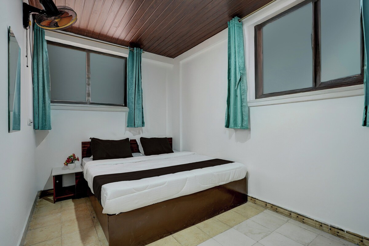 A bedroom with a bed, a nightstand, a window, and curtains.