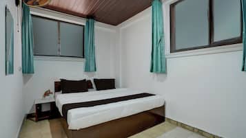 Un dormitorio con cama, mesita de noche, ventana y cortinas.