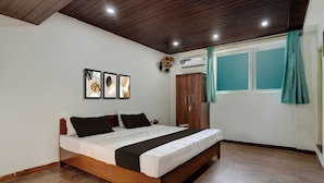 A bedroom with a bed, a wardrobe, a window with curtains, and wall-mounted artwork. - Hotel O Kodgehalli Railway Station (Bangalore)