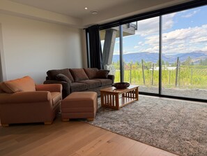 Ein modernes Wohnzimmer mit einem großen Fenster, einem Sofa, einem Sessel und einem Couchtisch.