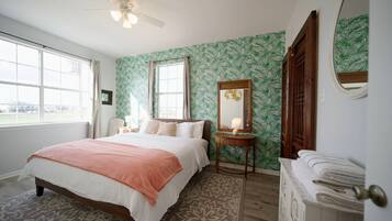A bedroom with a bed, a bedside table, a mirror, and a window.
