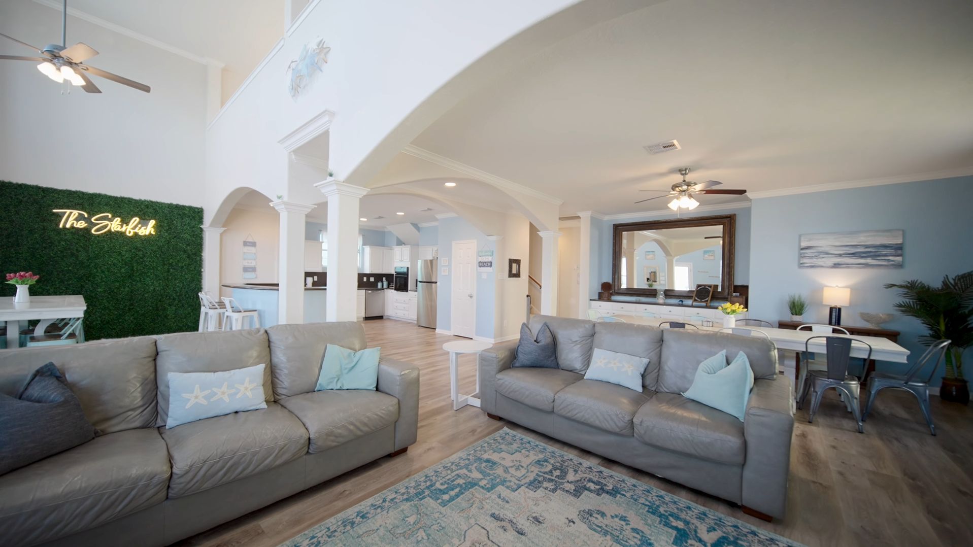 A spacious living room with two sofas, a dining area, and a kitchen in the background.