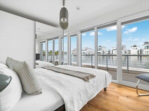A modern bedroom with a large bed, a view of the water, and a balcony. - NEW - Schleikubus (Kappeln)
