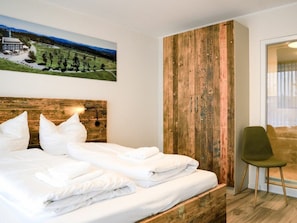 A hotel room with a bed, a wooden accent wall, a painting of a landscape, and a green chair. - Holiday Apartment 603 (Winterberg)