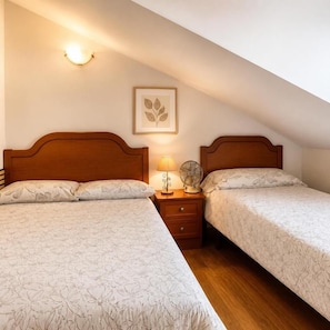 A bedroom with two beds, a bedside table with a lamp, a wall-mounted fan, and a framed picture. - Hostal Las Eras- Cubillos del Sil (Cubillos del Sil)