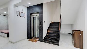 Un interior moderno con piso de mármol, una escalera y un banco.