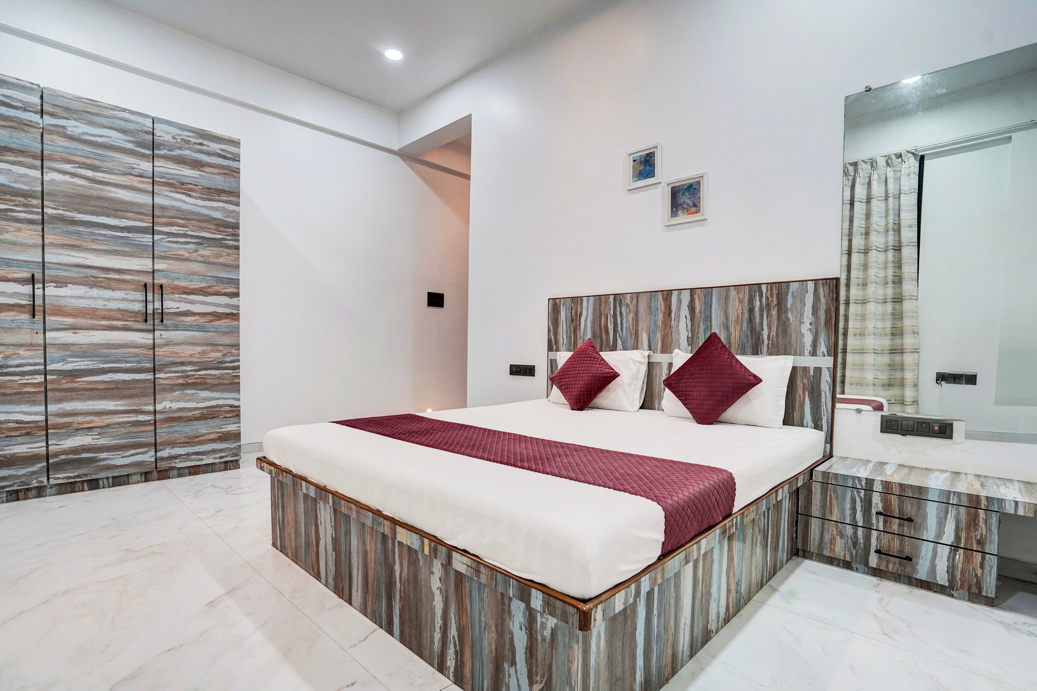 Een moderne slaapkamer met een groot bed, een kledingkast, een spiegel en een nachtkastje.