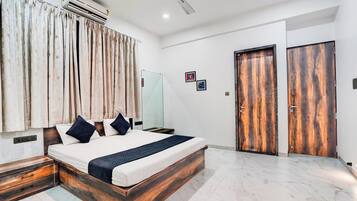 Habitación de hotel con cama, armario, ventilador de techo y aire acondicionado instalado en la pared.