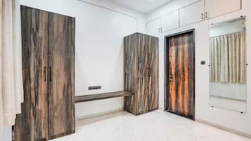 Un pasillo con piso de mármol, paneles de madera, un banco y una puerta con espejo.