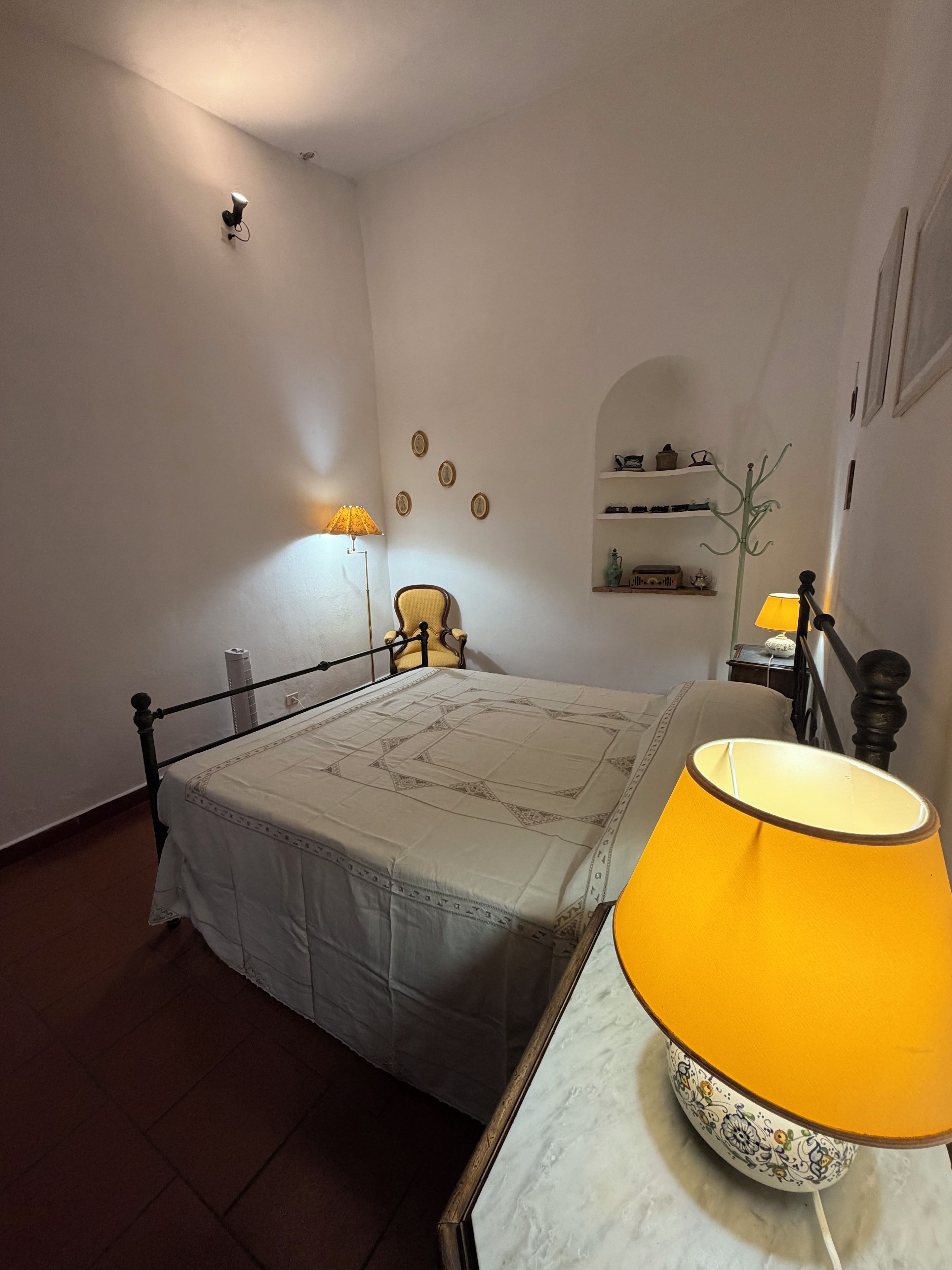 Une chambre à coucher comprenant un lit, une chaise, une table de chevet, une lampe et des éléments décoratifs sur les murs.
