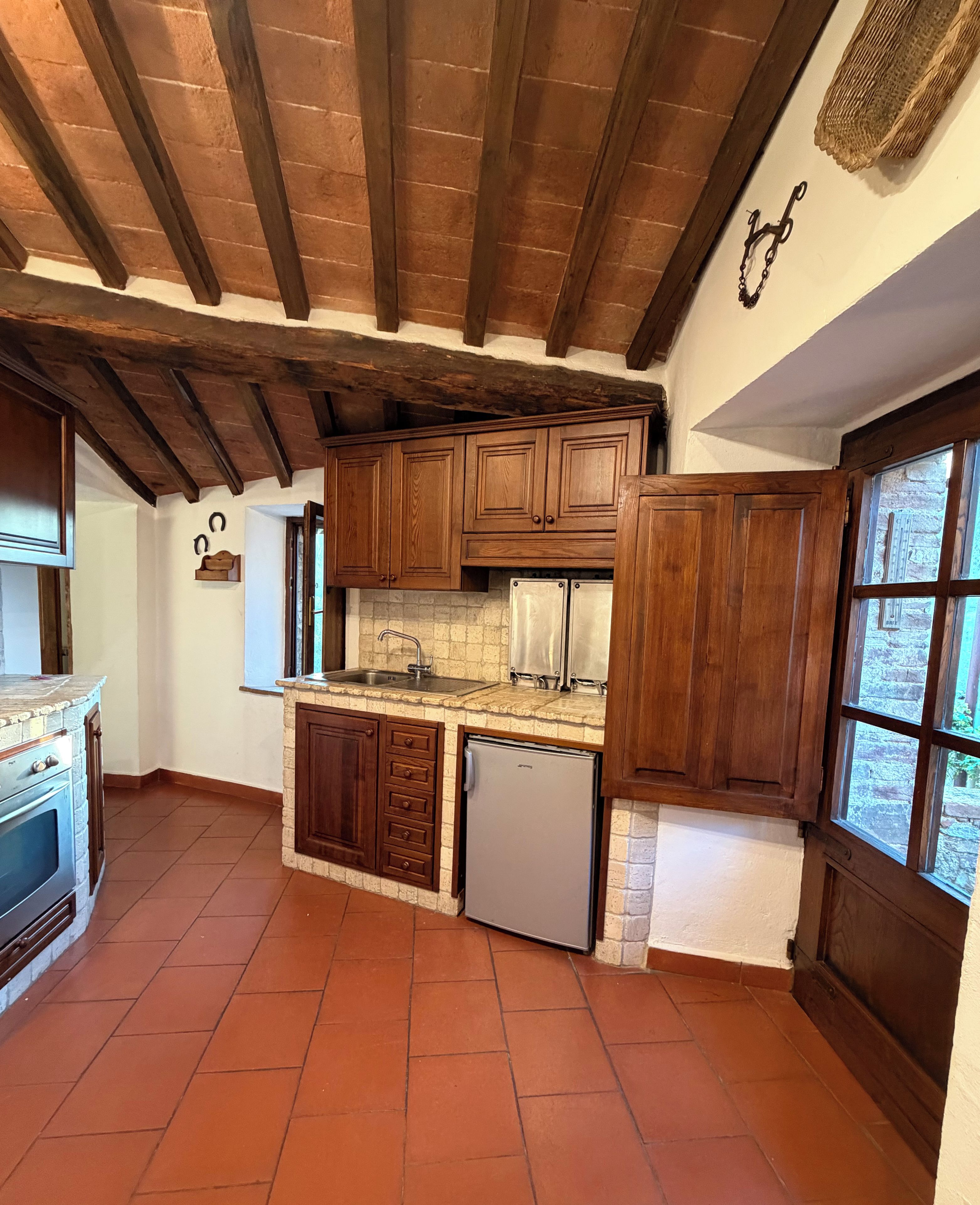 Une cuisine avec des meubles de rangement en bois, un four encastré et un réfrigérateur.