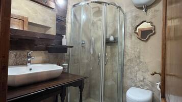 Ein Badezimmer mit Duschkabine aus Glas, Waschbecken, Toilette und Dachfenster.