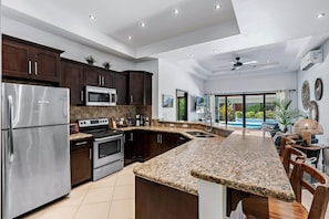 A modern kitchen with granite countertops, stainless steel appliances, and dark wood cabinets. - Beautiful 4-bedroom house with AC and private pool in Brasilito Beach (Brasilito)