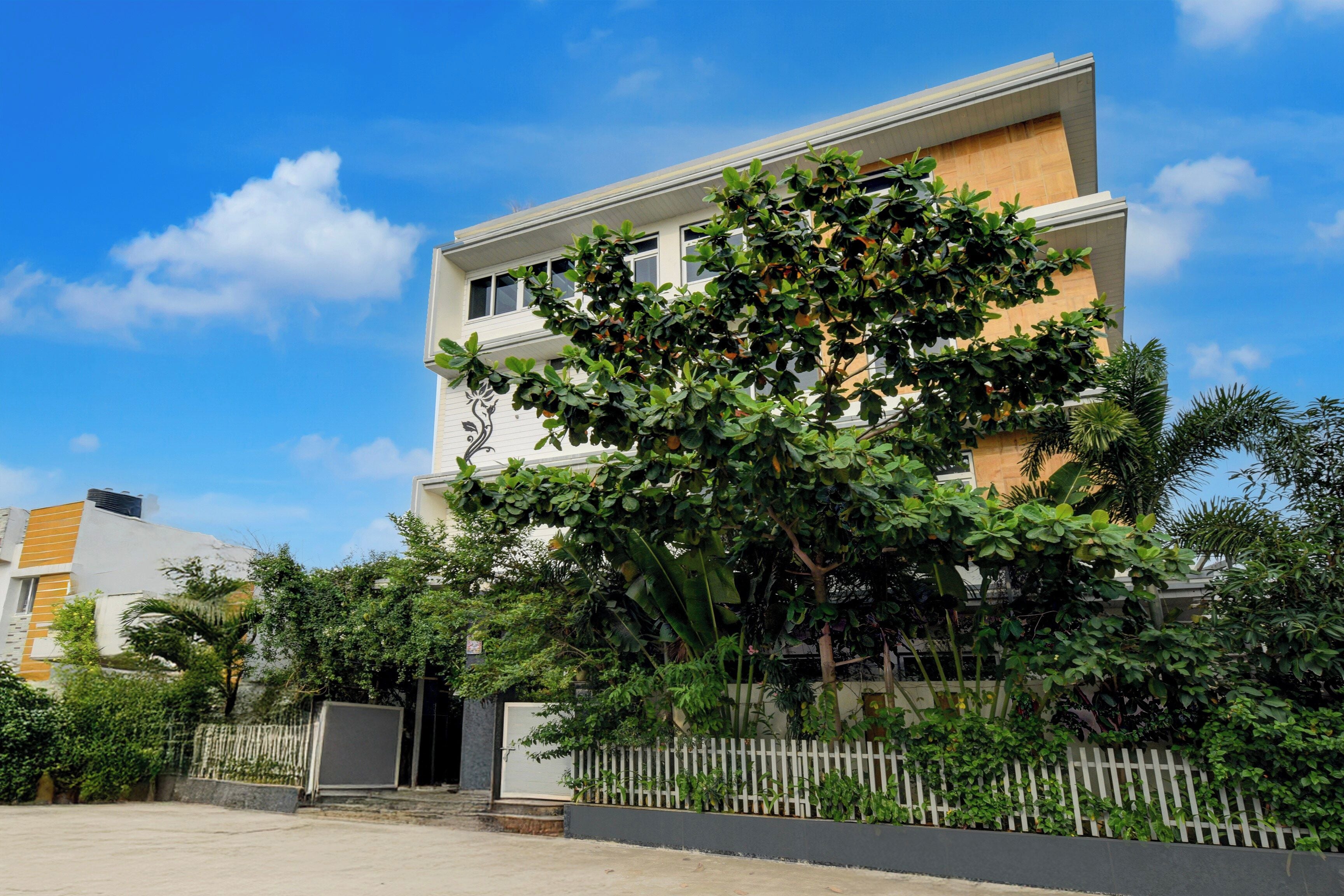 A modern two-story building with a white facade and a tree in front.