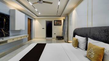 Une chambre à coucher moderne avec un grand lit, un ventilateur de plafond et un téléviseur fixé au mur.