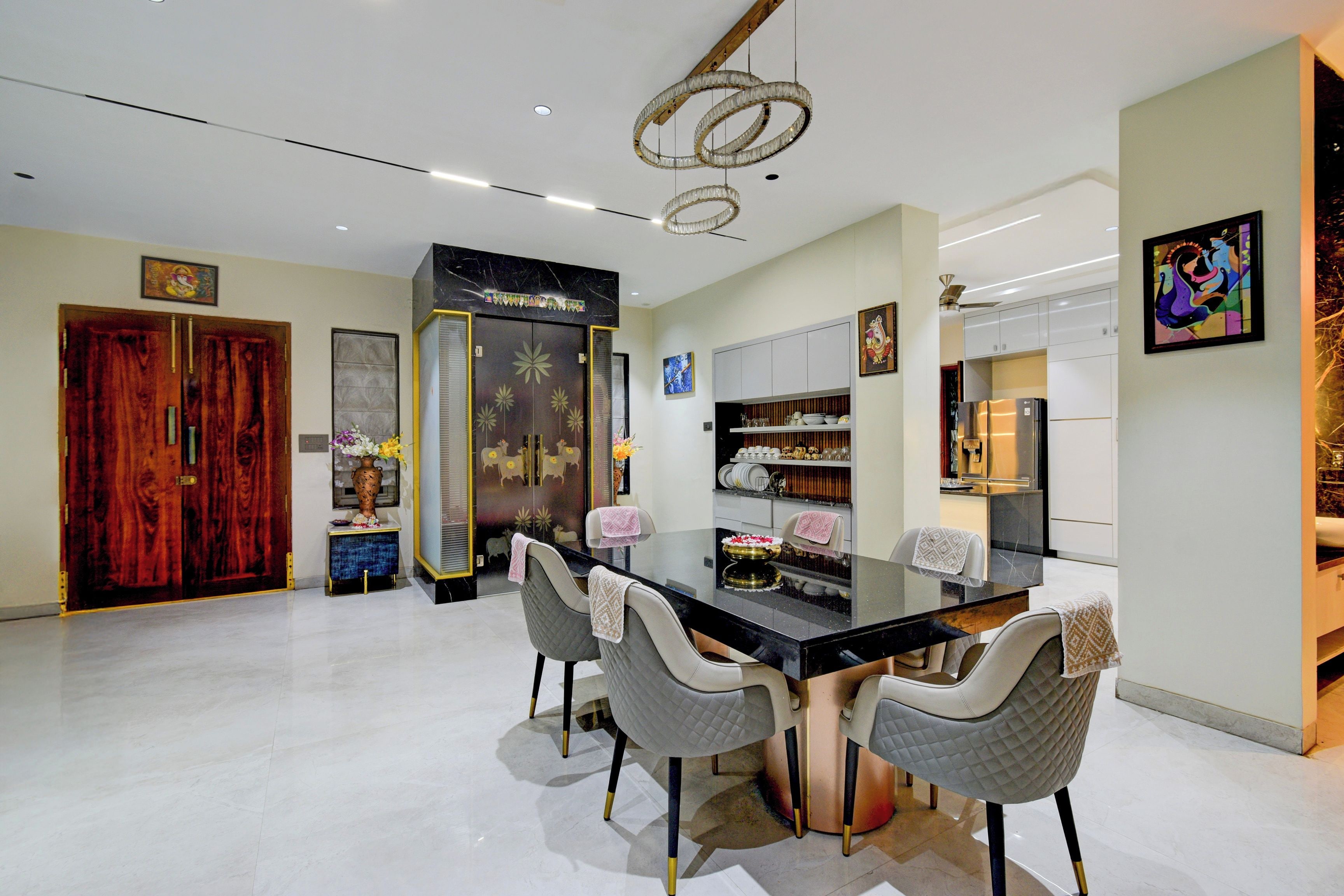 A modern kitchen with a black countertop, white cabinets, and a stainless steel refrigerator.