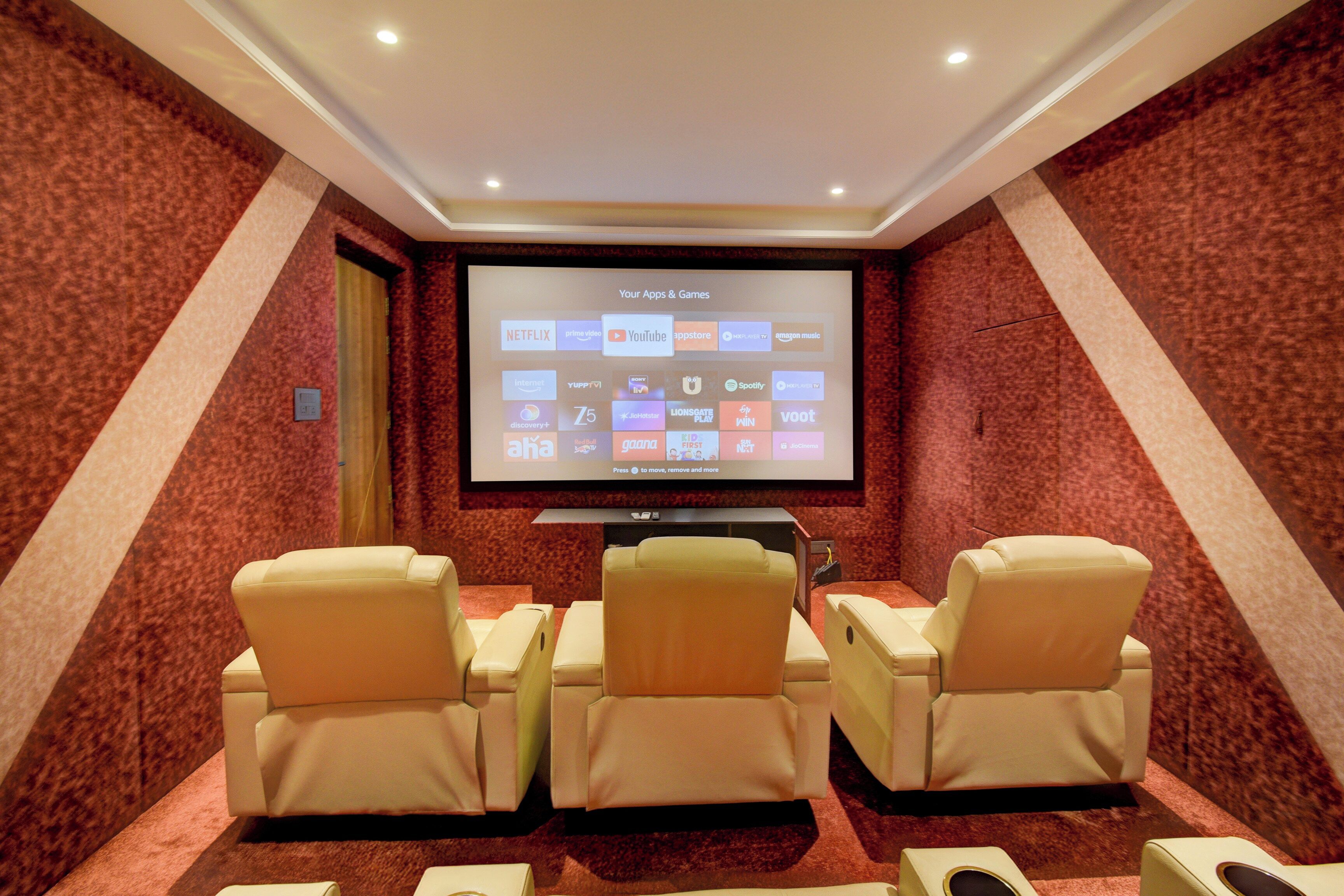 A home theater room with a large screen, comfortable seating, and a carpeted floor.