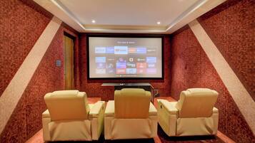 A home theater room with a large screen, comfortable seating, and a carpeted floor.