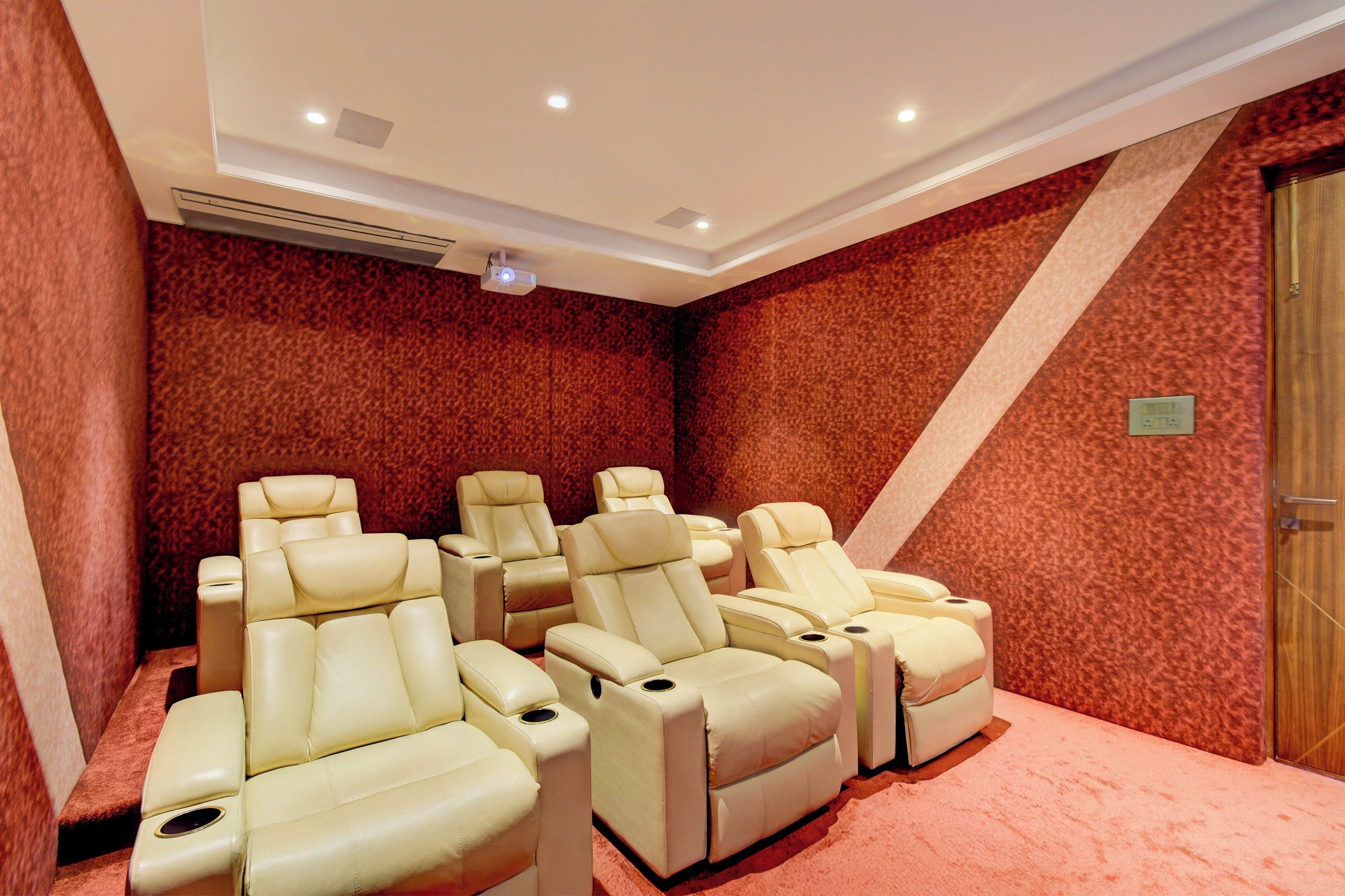 Une pièce équipée de quatre fauteuils de massage inclinables, avec des murs recouverts de moquette et un projecteur fixé au plafond.