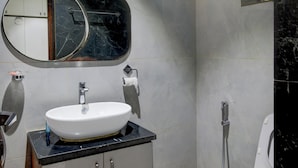 Een badkamer met een wit wastafel, een spiegel, een toilet en een douche.