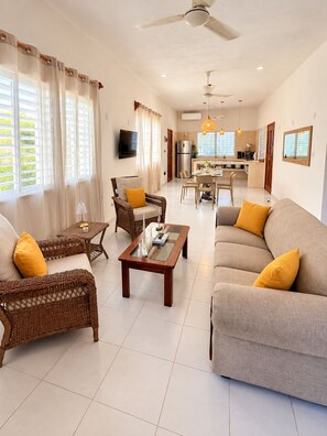 A living room with a sofa, chairs, a coffee table, and a television. - Mar-e-Luna | Private Pool & Beach Living in Chicxulub (Chicxulub)