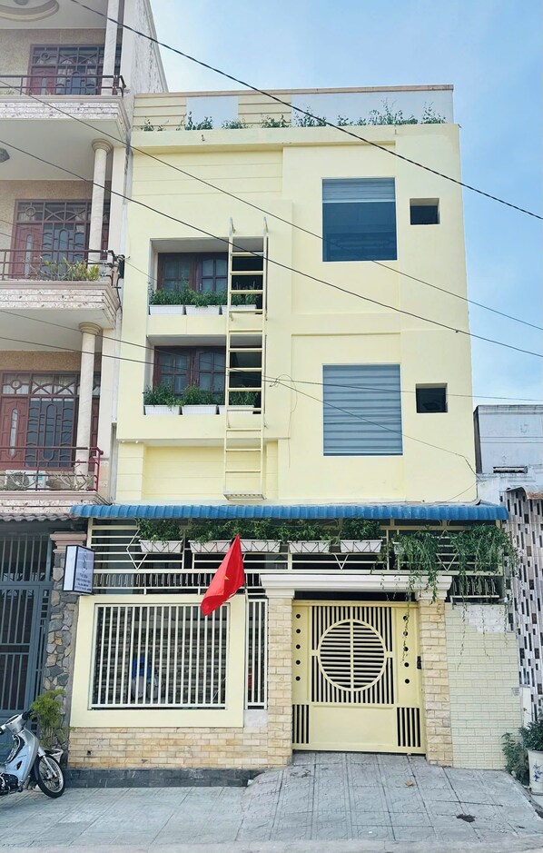 A multi-story building with balconies, a gated entrance, and a parked motorcycle.