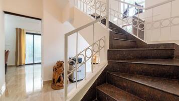 A staircase with a metal railing, a statue, and a Tuffon machine in a well-lit room with a large window.