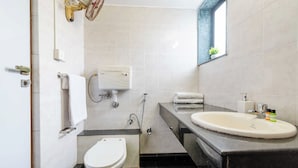 Casa de banho compacta com sanita, bidé e lavatório.