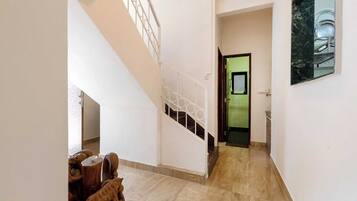 Um corredor com escada, área de jantar com mobiliário de madeira e uma porta verde que dá para outro cômodo.